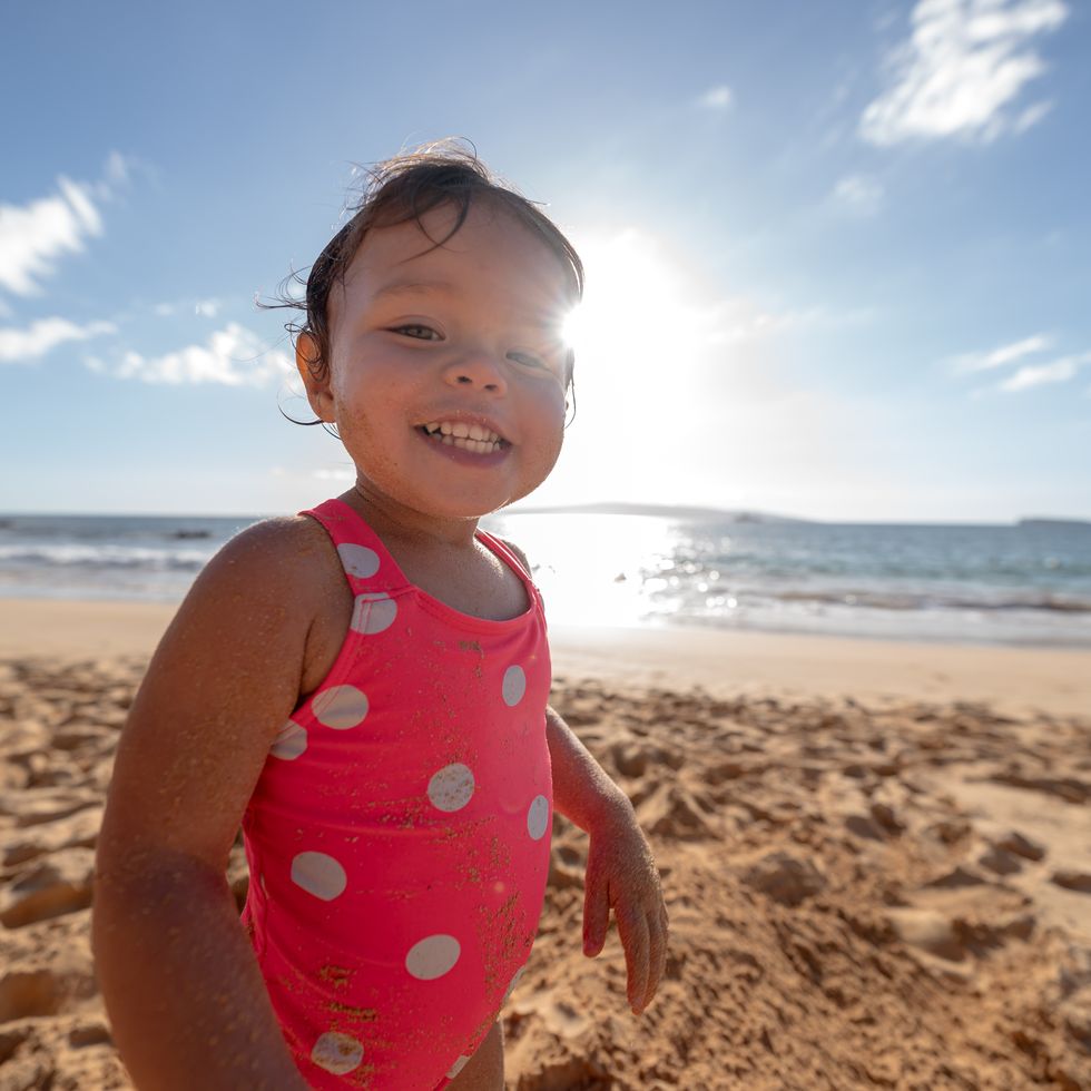 niña feliz en la playa con bañador