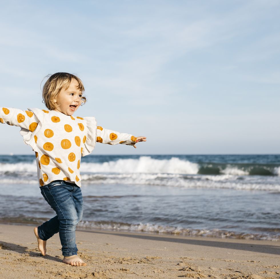 happy little girl running barefoot on the beach