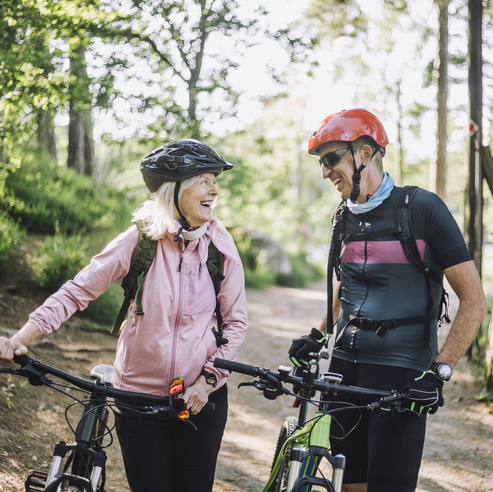 happy male and female friends talking to each other holding cycles