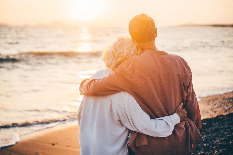 happy mature couple enjoying beautiful sunset at the beach retirement vacation concept