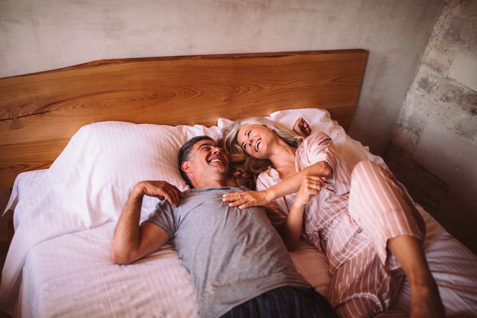 happy mature couple laughing together while lying down in bed