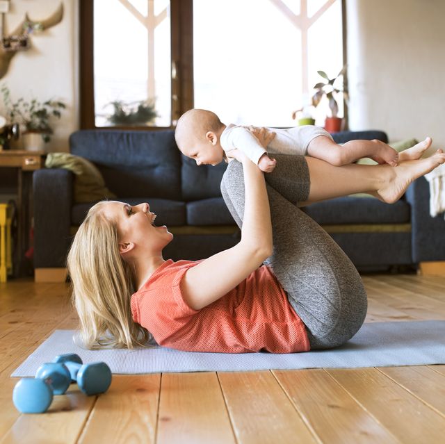 happy mother lifting up baby at home lying on mat