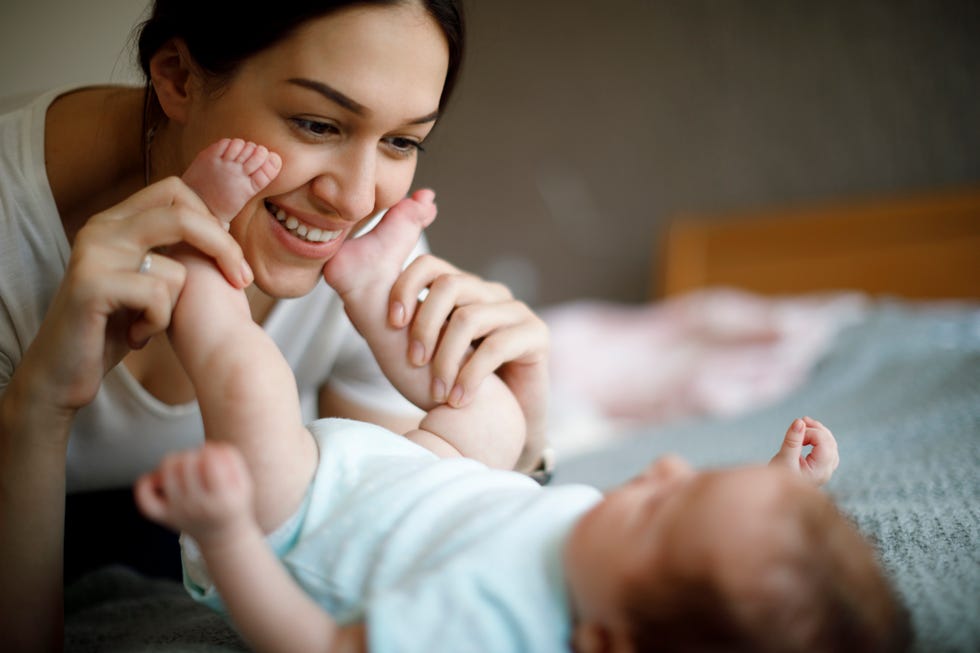happy mother playing with her baby in the bed