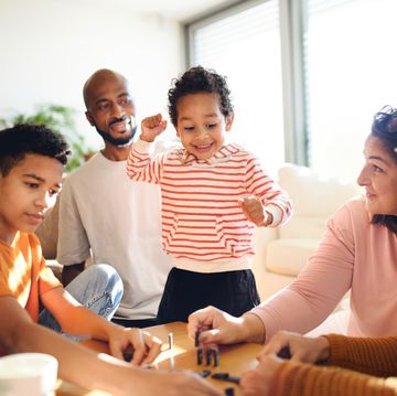 happy multiracial family with three children playing domino at home