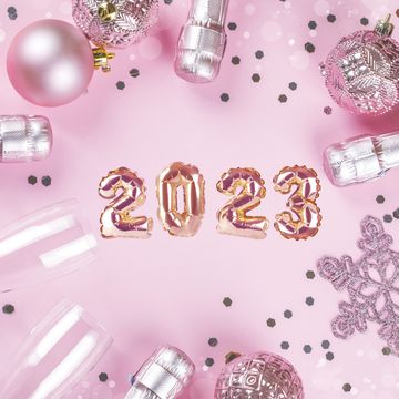 happy new year celebration background champagne bottles, glasses and christmas ornaments on pink background flat lay, top view with copy space
