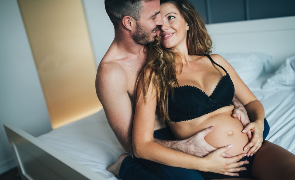 happy pregnant woman enjoying with husband in bedroom