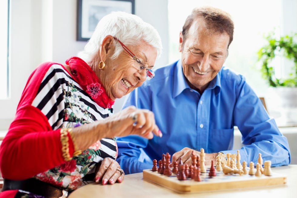 winter date ideas - Happy senior couple playing chess at table in nursing home