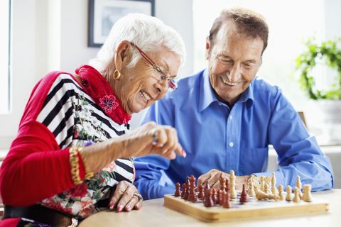 winter date ideas - Happy senior couple playing chess at table in nursing home