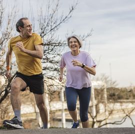 happy senior couple running in the park