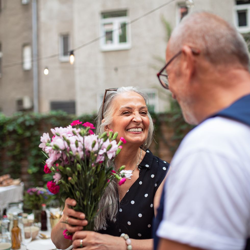happy senior woman getting bouquet from her husband outdoors in garden
