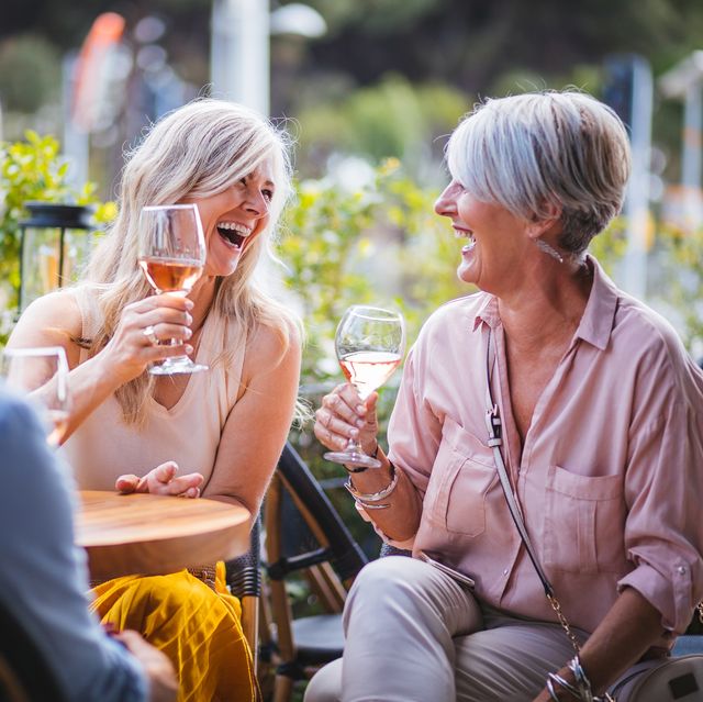 Happy senior women drinking wine and laughing together at restaurant