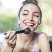Happy teenage girl applying makeup