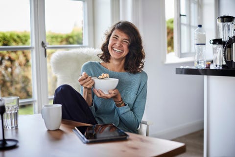 happy woman having breakfast at dining table