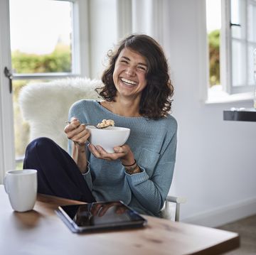 happy woman having breakfast at dining table
