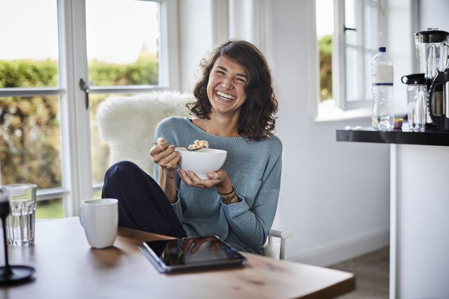 happy woman having breakfast at dining table