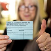 happy woman holding covid 19 vaccination record card