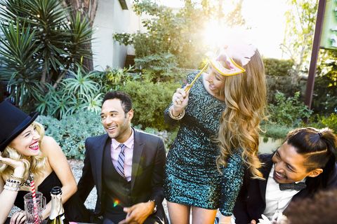 new years colors woman wearing a glittery green dress holding a mask at a party