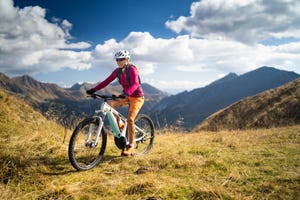 happy woman on electric mountain bike high up in european mountains