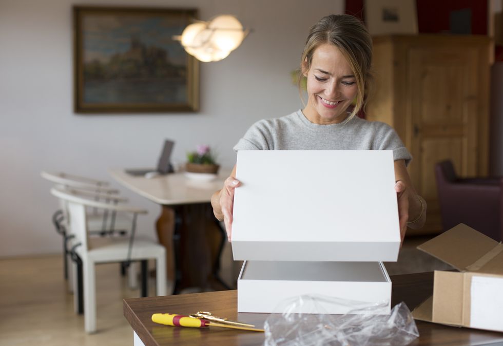 happy woman opening parcel at home