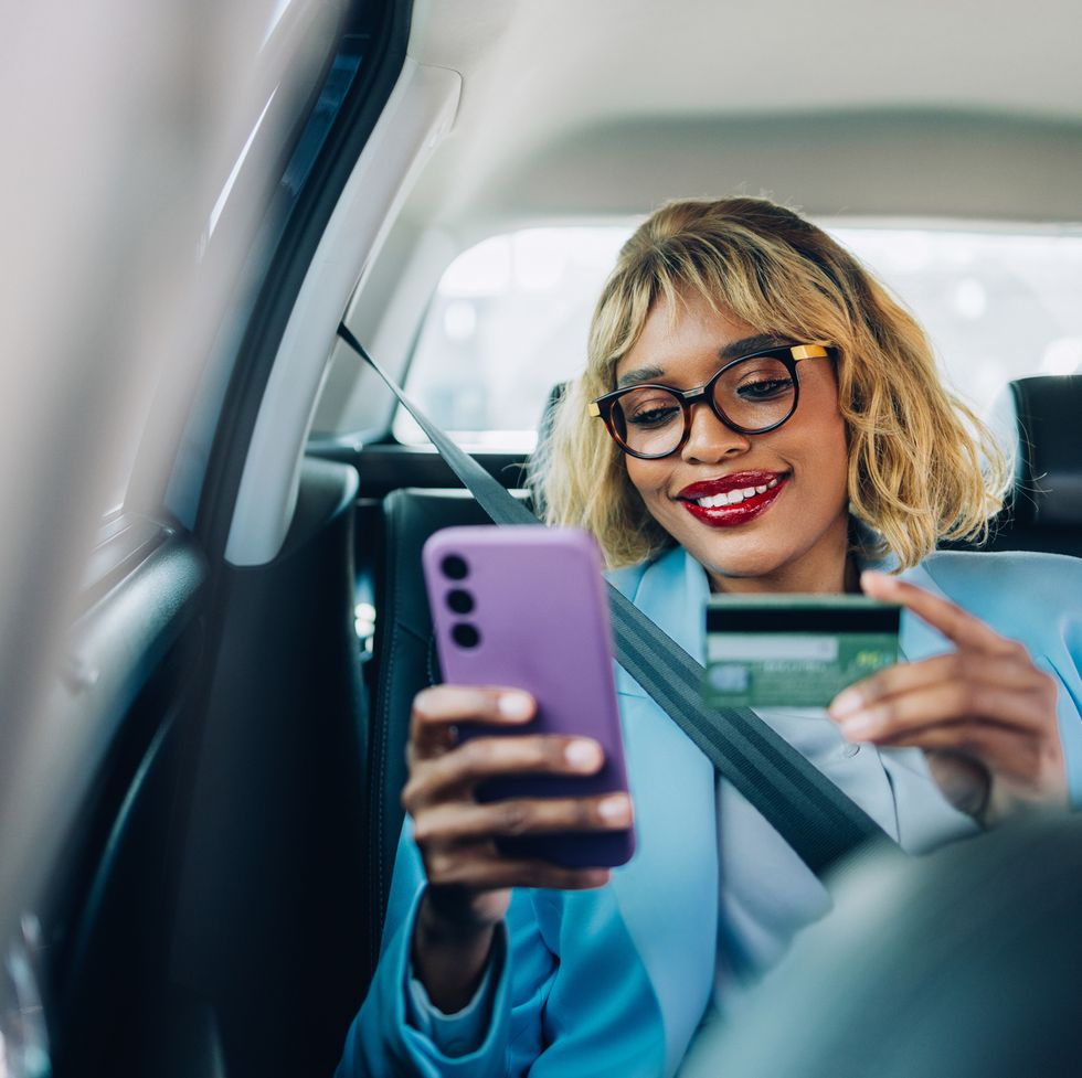 happy woman shopping online with credit card in car