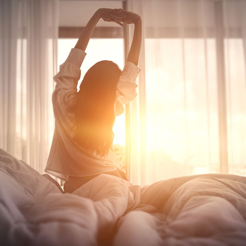 happy woman stretching in bed after waking up happy young girl greets good day