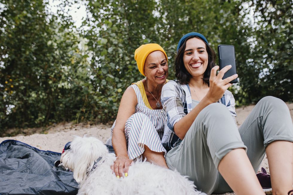 happy women taking selfie through mobile phone at park