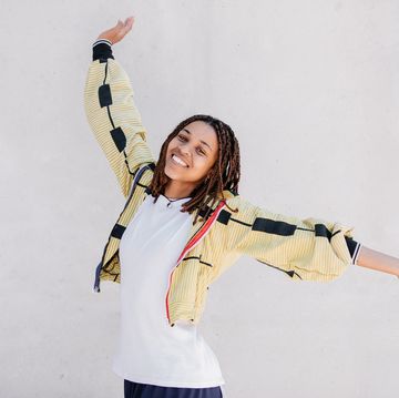 happy young beautiful woman wearing yellow and raising arms in the air