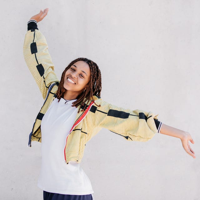 happy young beautiful woman wearing yellow and raising arms in the air