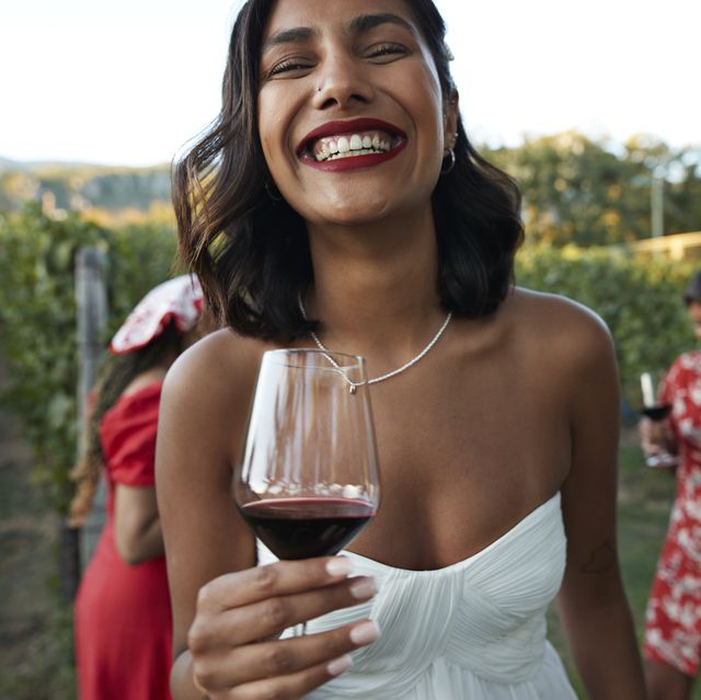 happy young bride holding wineglass at vineyard