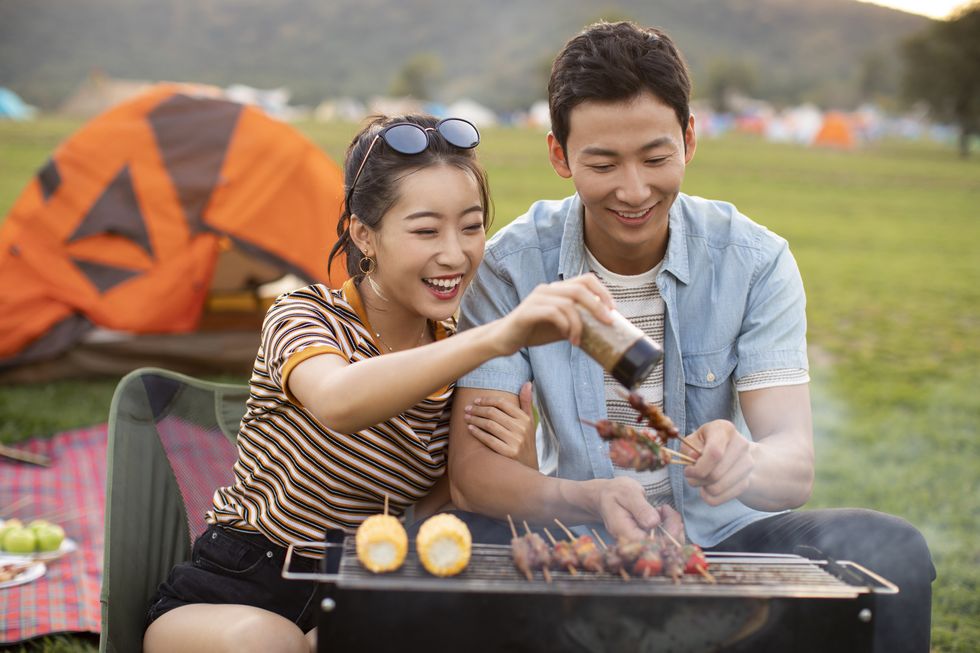 happy young chinese couple barbecuing outdoors