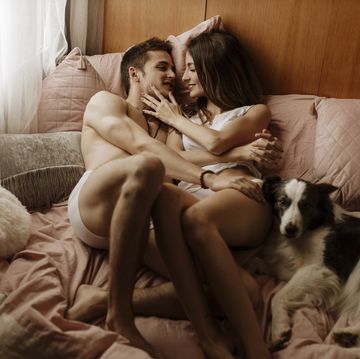 happy young couple and dog lying in bed