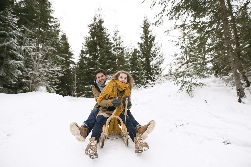 happy young couple on sledge in winter forest
