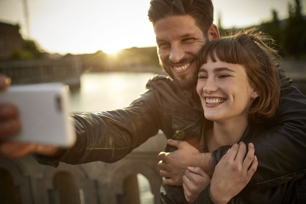 happy young couple taking selfie by the riverside