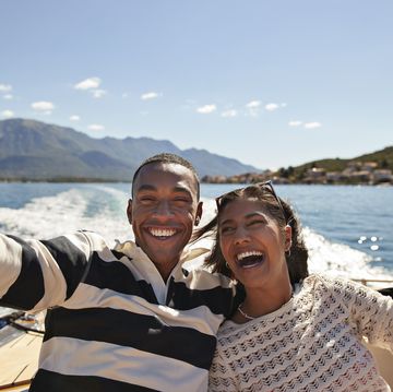 happy young couple taking selfie in boat