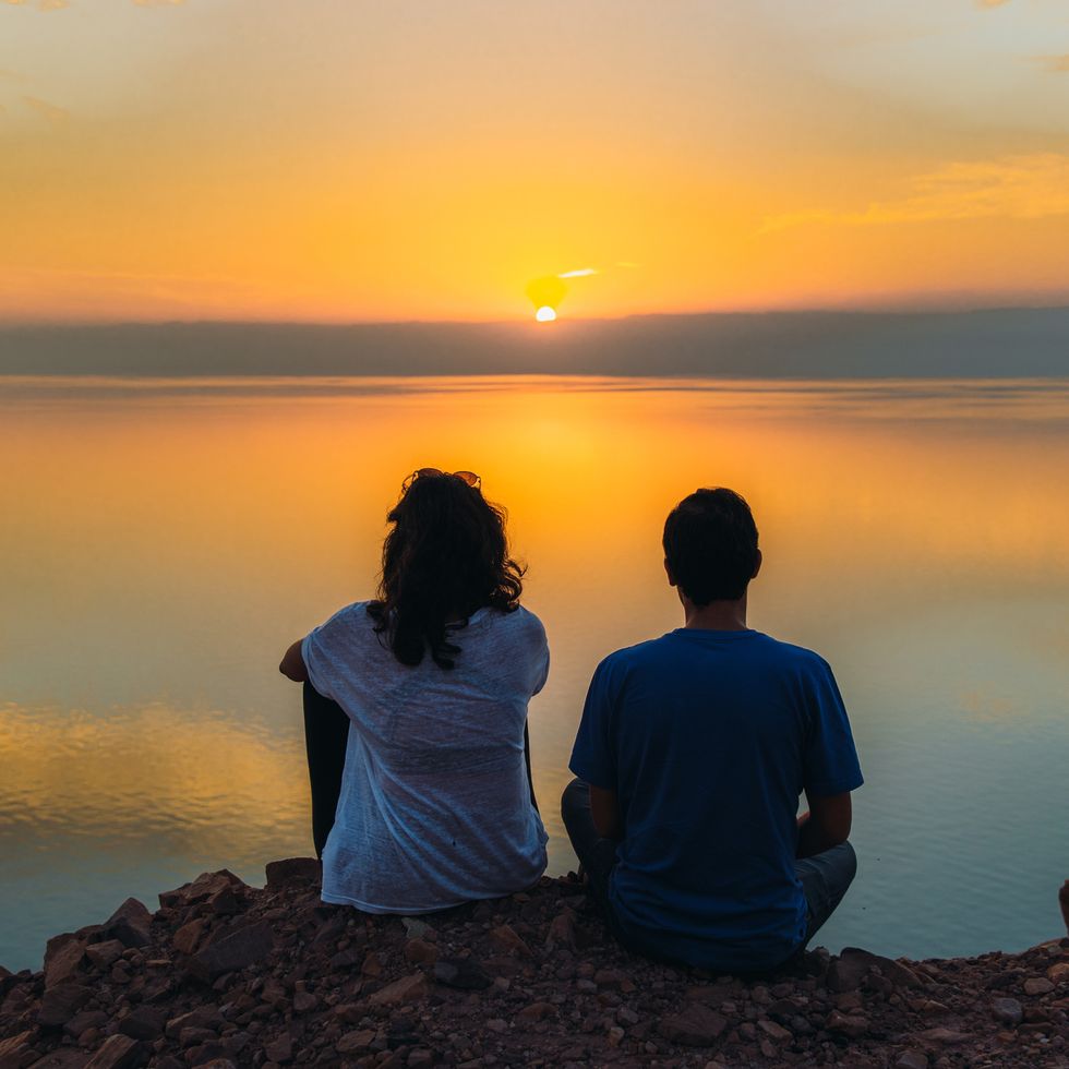 happy young female and male contemplating the scenic sunset above the dead sea in jordan