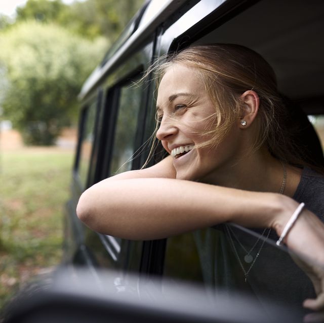 happy young woman looking out of car window