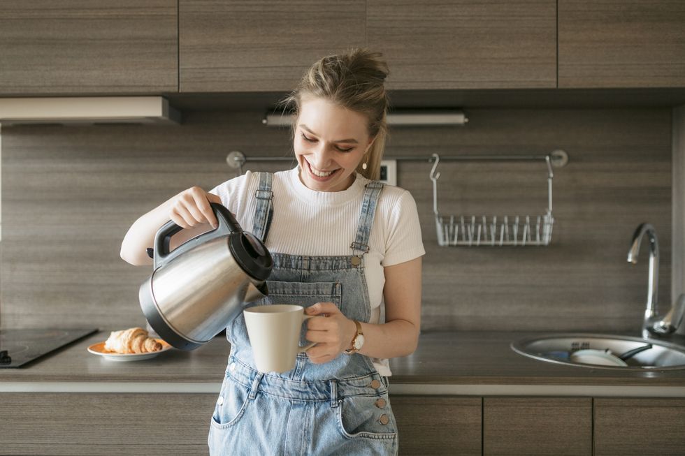happy young woman pouring herself some morning coffee