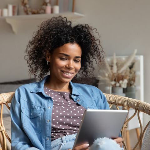 happy young woman reading book, ebook on tablet at home