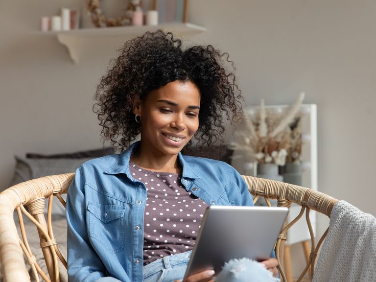 happy young woman reading book, ebook on tablet at home