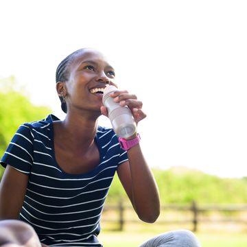 happy young woman sipping flavoured drink from bottle