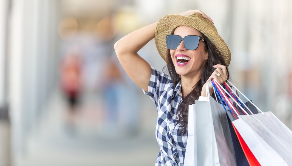 happy young woman with shopping bags in front of mall