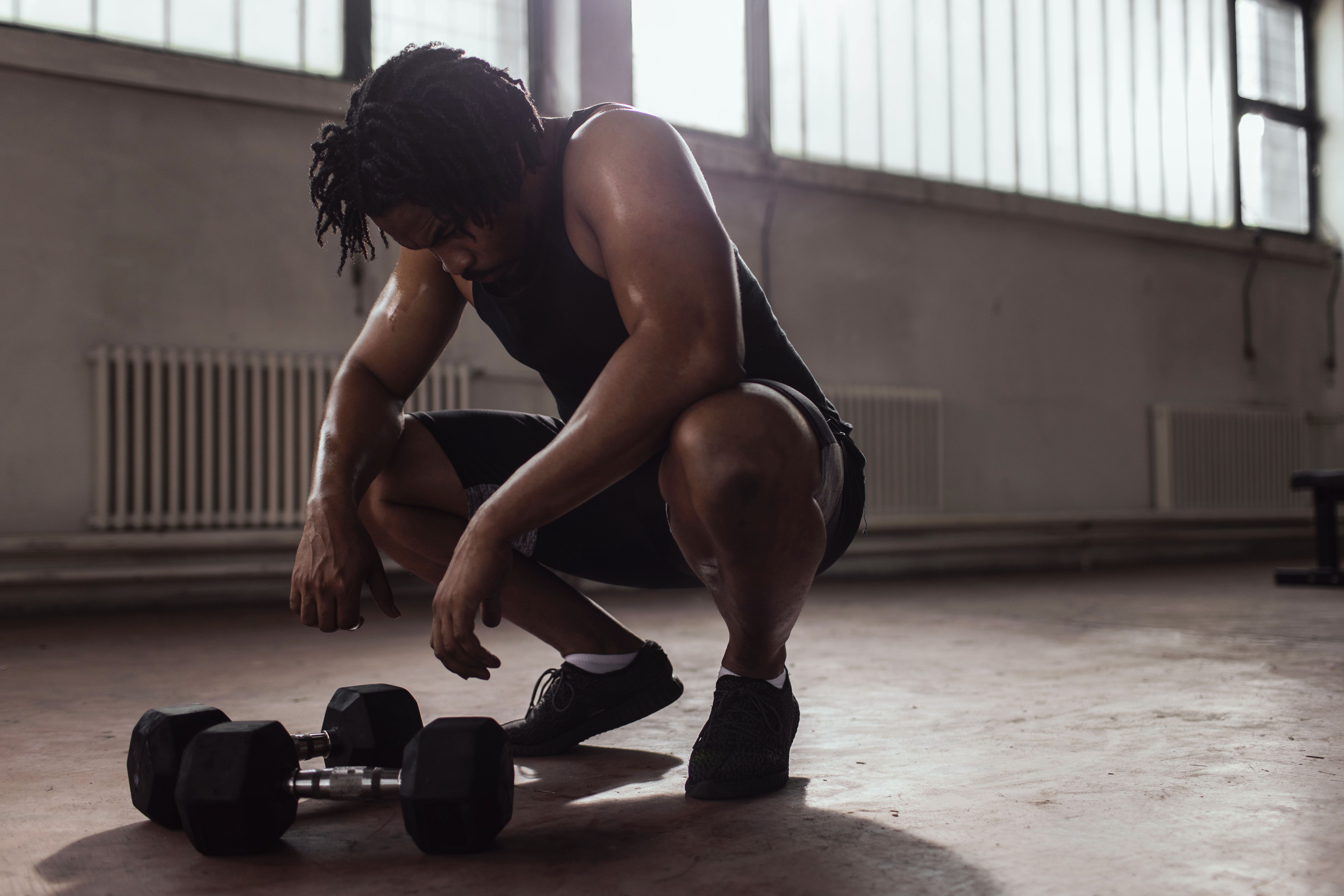hard workout. Muscular black man doing exercises with dumbbells