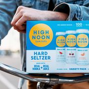 man on bike holding variety pack of high noon hard seltzer