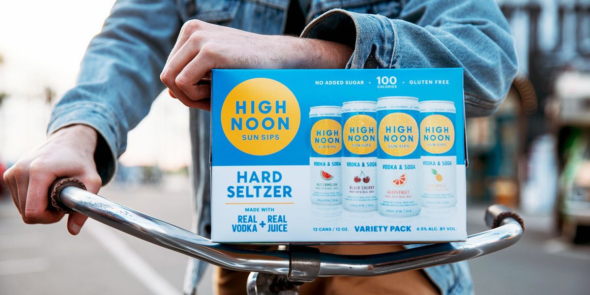 man on bike holding variety pack of high noon hard seltzer