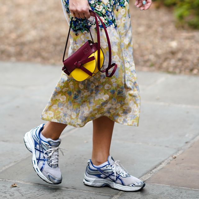london, england   september 16 a guest wears asics blue and gray sneakers, a burgundy and yellow leather loewe bag, a floral print skirt, during london fashion week september 2019 on september 16, 2019 in london, england photo by edward berthelotgetty images