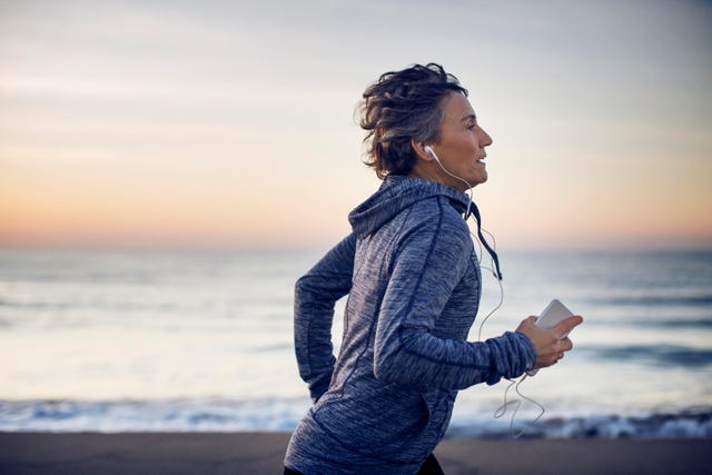 vrouw hardlopen over strand met telefoon in hand