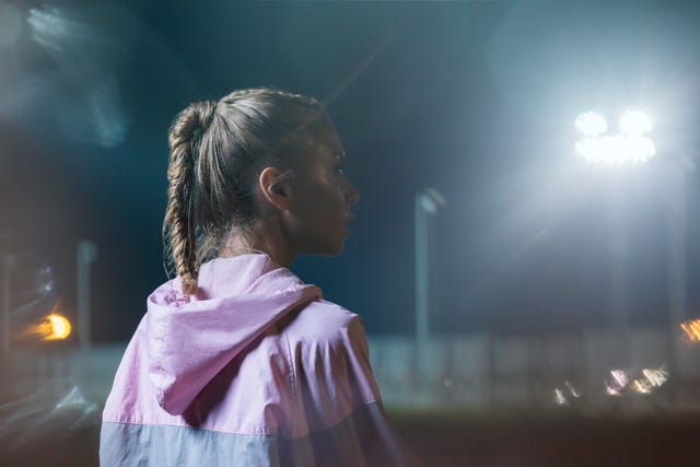 portrait of a female urban runner at night, midshot, looking away from camera, low key bokeh background, landscape composition, backlit, one female only aged 24 to 28