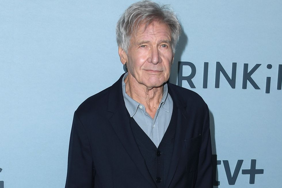 harrison ford, an older man standing smiling at the camera, wearing dark blue jeans and jacket