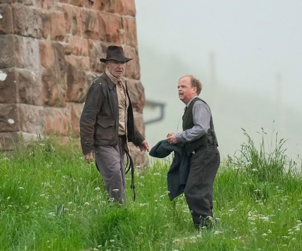 harrison ford and toby jones walk through grass at leaderfoot, melrose, scottish borders filming for indiana jones