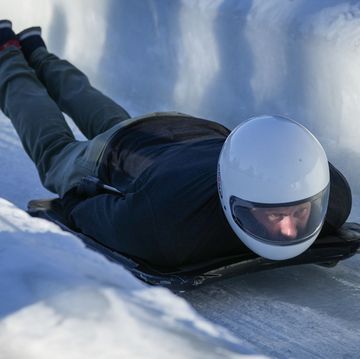 el duque de sussex con casco y sobre una tabla en un tunel de hielo haciendo bobsleigh